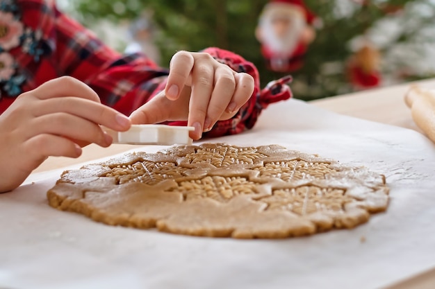 Christmas pastries. The girl making gingerbread. Detail of the hand.