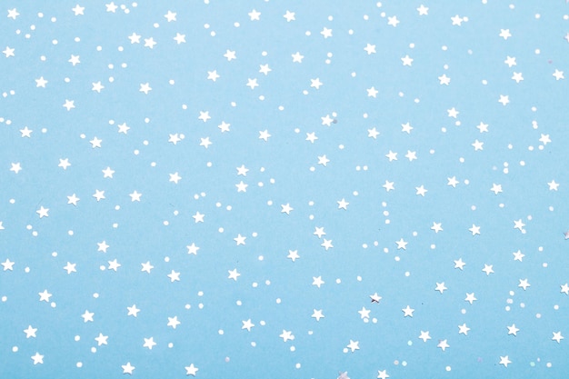 Christmas pattern made of silver stars on blue background Winter concept Flat lay