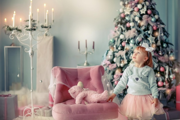 Christmas photo of a 3 year old girl near a beautiful Christmas tree.