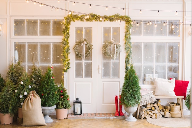 The Christmas porch is decorated with small Christmas trees and lanterns