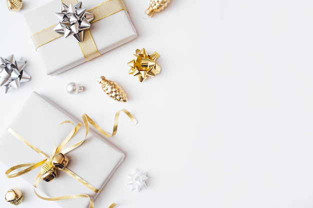 Christmas presents and gifts and gold and silver decorations on white background. Merry christmas, New Year holiday concept. Flat lay, top view, copy space.