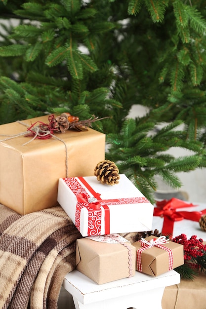 Christmas presents  near Christmas tree on light surface