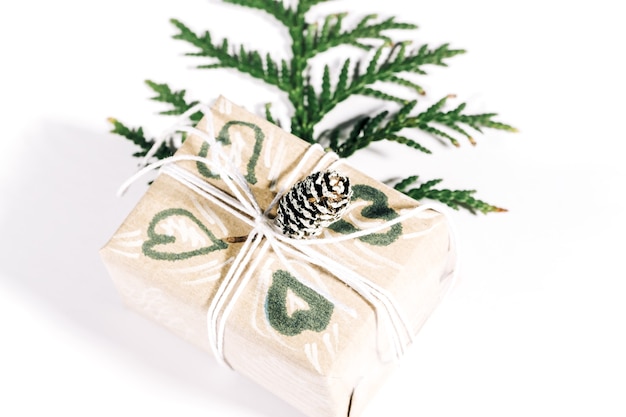 Christmas presents with gift box decorated with pine cones and twigs on a white background, preparation for holidays. Christmas presents and New Year. Handmade. Selective focus,