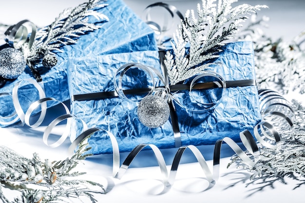 Christmas presents with gift box in silver blue color decorated with pine cones and twigs on white background, preparation for holidays. Christmas presents and New Year. Handmade. Selective focus.