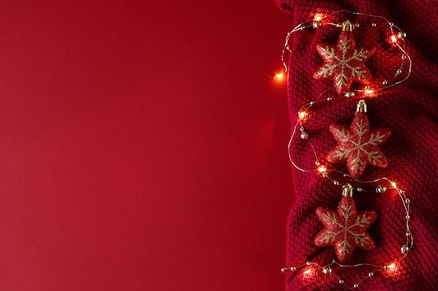 Christmas red background with red Christmas toys beads and a garland on a burgundy knitted fabric