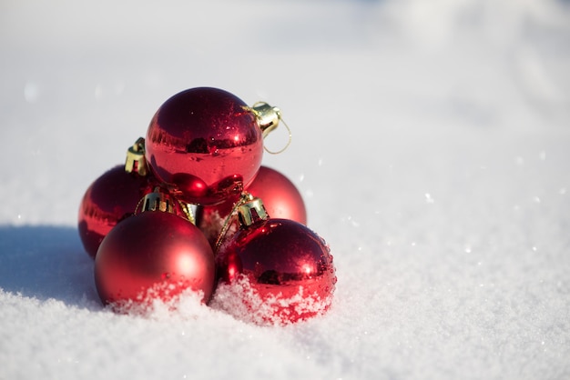 christmas red balls decoration in fresh snow background on beautiful sunny winter day