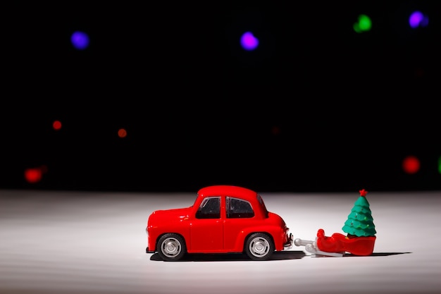 Christmas red car carrying a sleigh with a christmas tree on christmas eve