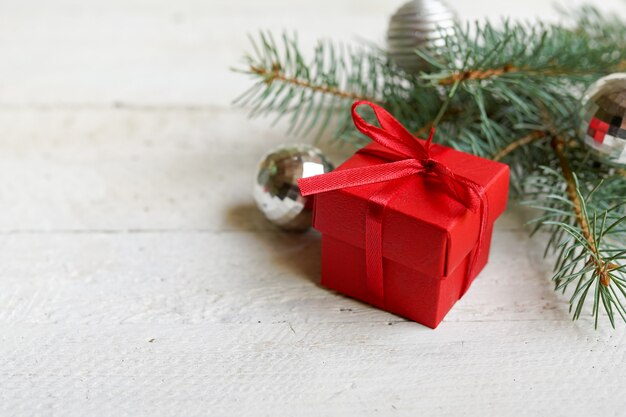 Christmas red gift box with tree branches decorating on white wood, copy space