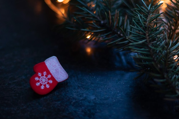 Christmas red mitten with snowflake on Christmas tree branch with garland Bokeh effect Premium photo