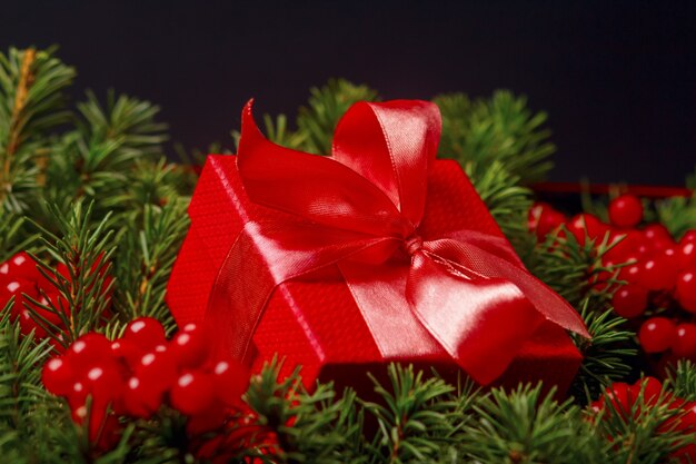 Christmas red present gift box with satin bow decorated with red berries.