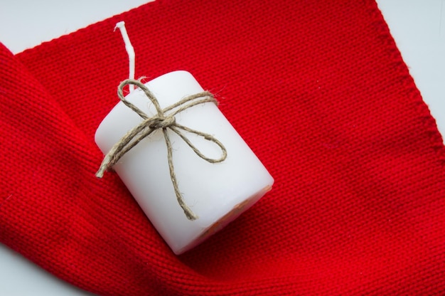 Christmas red scarf and a white candle tied with twine copy space Xmas time