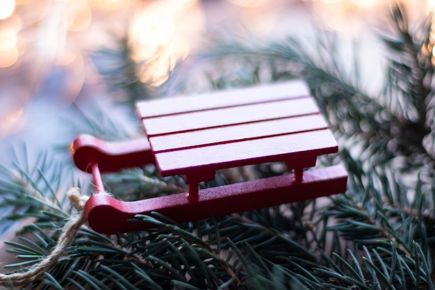 Christmas red sleigh on Christmas tree branch with garland Bokeh effect Premium photo