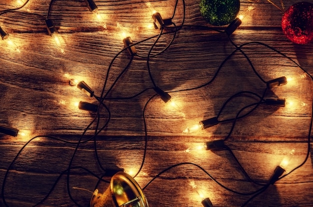 Christmas rustic light bulb background with jingle bells and ball on vintage wood panel ba