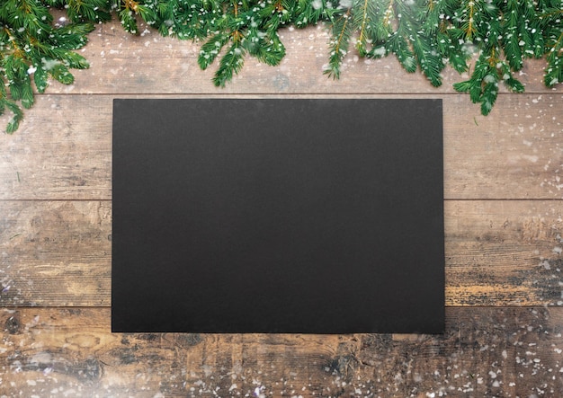 Christmas rustic mockup sheet of black paper lies on an old table decorated with Christmas fir branches and cones christmas dinner menu mockup