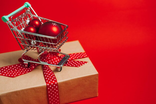 Christmas sale shopping web banner with mini trolley cart with gift box and red xmas ornaments balls