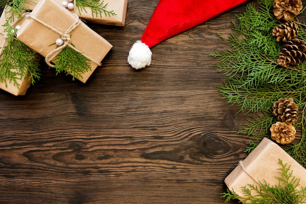 Christmas santa hat and gift boxes on dark wooden board with copy space