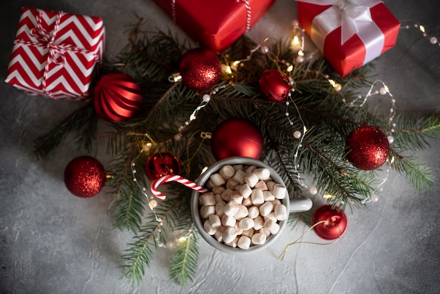 Christmas Setting with Hot Chocolate in a Fancy Sweater Mug with Marshmallows, Candy Canes, Wooden Deer and Xmas Lights on the Background