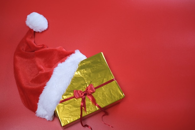 Christmas shopping. List of purchases and gifts for the new year. Santa claus hat lies on a gold box on a red background.