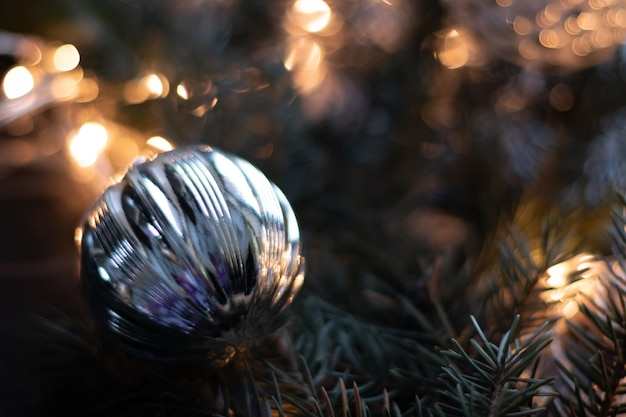 Christmas silver ball on Christmas tree branch with garland Bokeh effect Premium photo