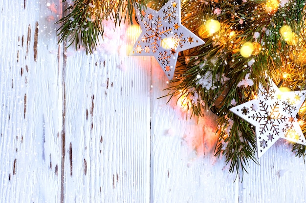 Christmas snowy background. Fir branches with burning garland.