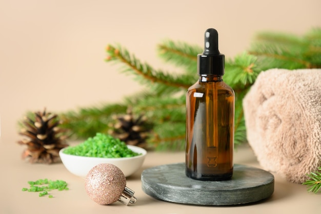 Christmas Spa wellness concept with cosmetic aroma oil pine cones on beige background