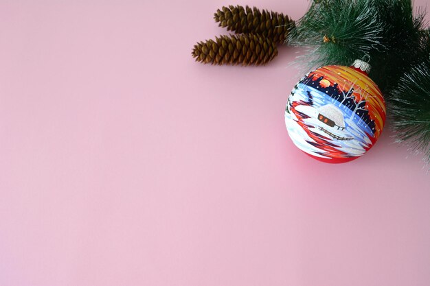 christmas sphere with pine branch and cones on pink background, copy space