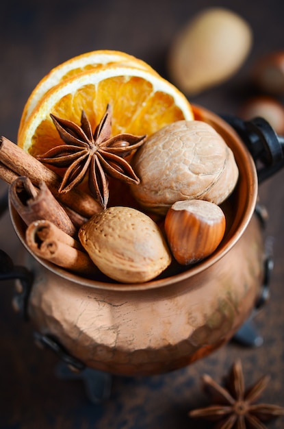 Christmas spices, nuts and dried oranges on a dark wooden table