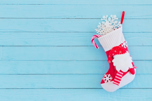 Christmas stocking with gifts hanging on blue wooden background