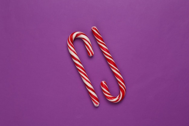 Christmas striped candy canes on purple background