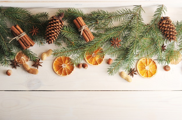 Christmas surface with Christmas tree branches, pine cones, dried oranges, cinnamon and peanut