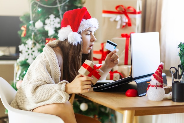 Christmas surprised woman looking on laptop doing internet shopping around present boxes and christm