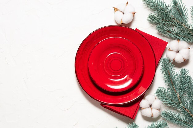 Christmas table setting with blank red plate, napkin and fir tree branches on white 