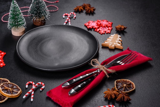 Christmas table setting with empty black ceramic plate fir tree and black accessories