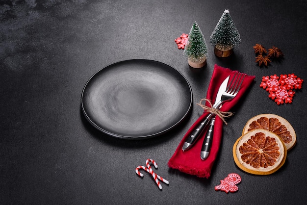 Christmas table setting with empty black ceramic plate fir tree and black accessories