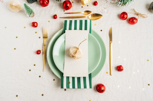 Christmas table setting with vintage tree toys, shiny confetti, golden cutlery on light linen tablecloth