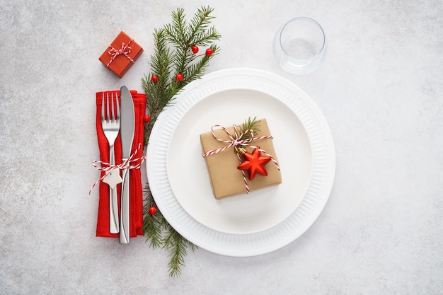 Christmas table setting with white plates, red napkin and cutlery