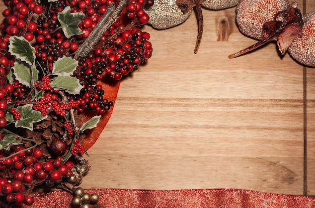 Christmas theme frame background with holly bush and decorations on wooden surface Top Copy space