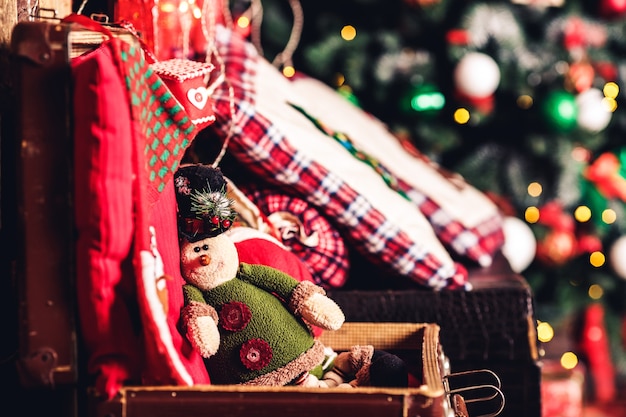 Christmas toy elf sitting on suitcase on background of Christmas tree.