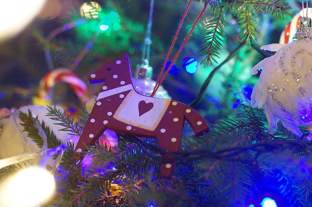 Christmas toy horse hanging on the branches of the Christmas tree.