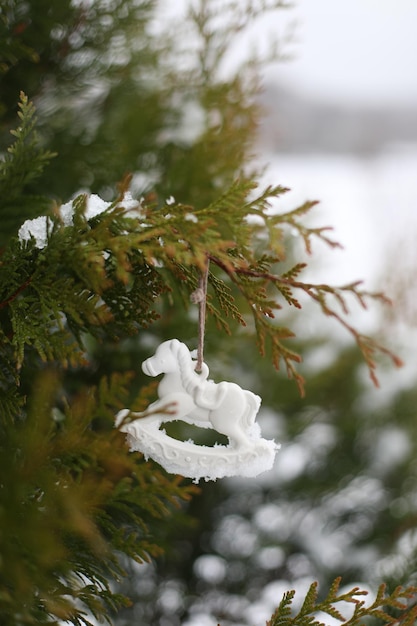 Christmas toy horse hanging on a green branches in the snow in winter Christmas tree toy horse gift New Year decor