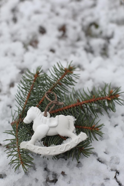 Christmas toy horse hanging on a green branches in the snow in winter Christmas tree toy horse gift New Year decor