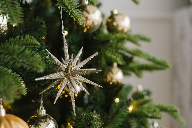 Christmas toy star and balls hang on the tree, decorated with lights