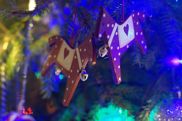 Christmas toys hang on branches surrounded by glowing garlands.