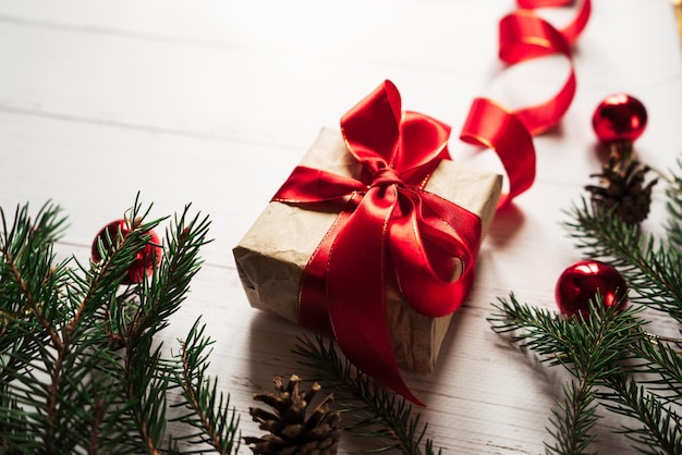 Christmas toys pine cones a gift with a red ribbon spruce branches on a white wooden table 1