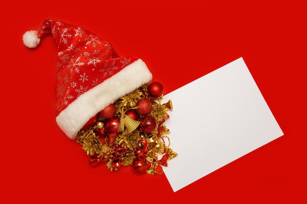 Christmas toys spill out of santa's hat next to an empty white sheet on a red background copyspace christmas content