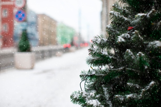 Christmas tree on the background of a blurred city and snowfall