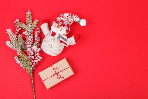 Christmas tree branch with toys and a gift on a red background closeup