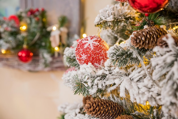 Christmas tree branches on blurred background with red balls and golden decor berries garland cone