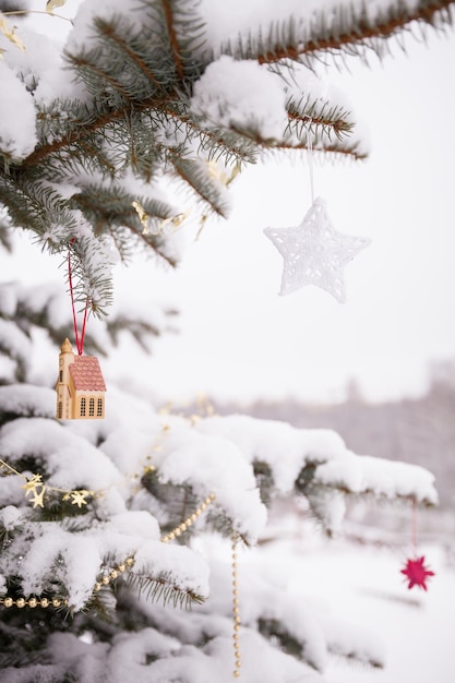 Christmas tree decorated with red and gold toys outdoor and covered with snow