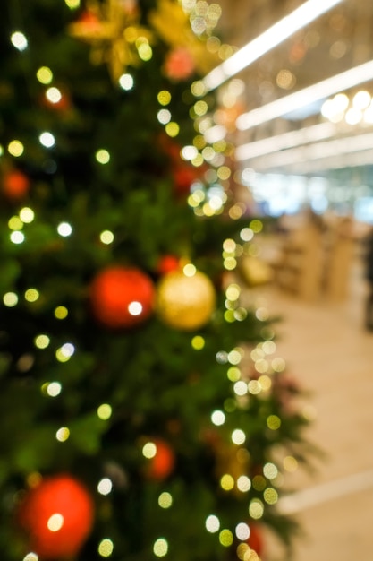 Christmas tree decorated with toys and garlands with shop lights blurred background